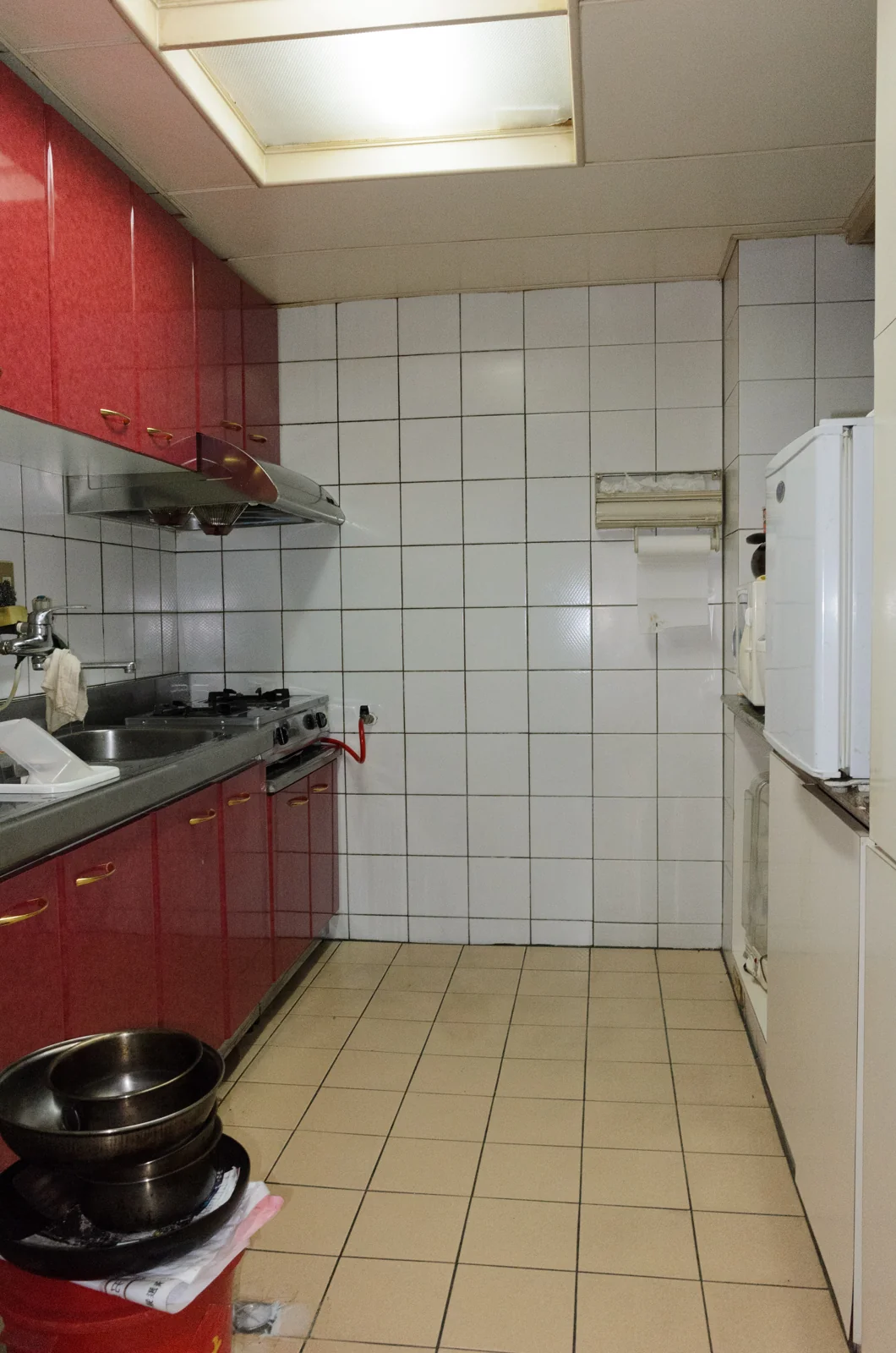 dapur sempit dengan kabinet di dua sisi lorong dan dinding keramik putih