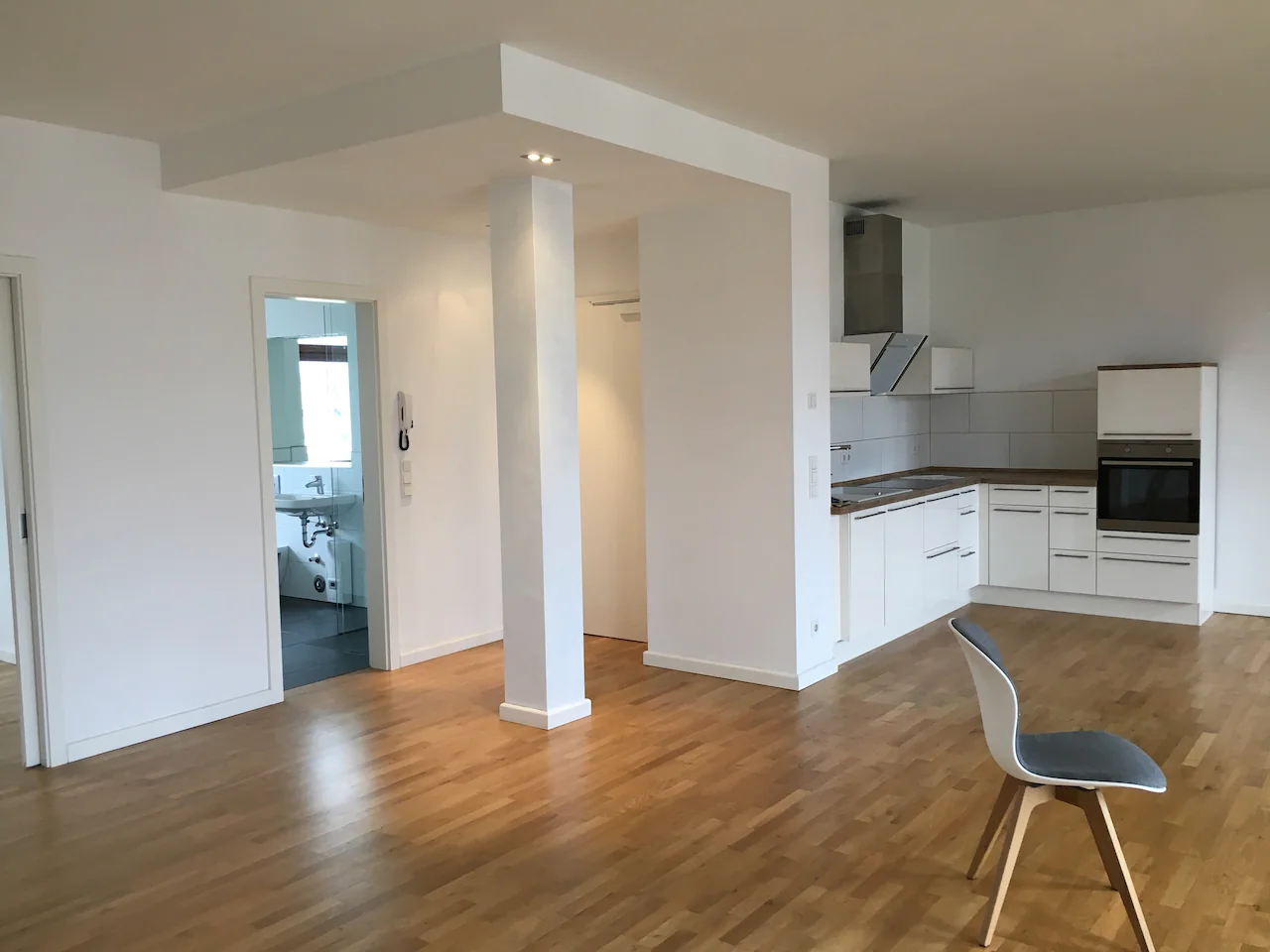 kitchen set putih satu dinding di apartemen kosong berlantai kayu