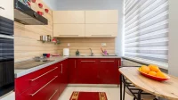 dapur kecil bentuk L dengan kabinet merah dan meja makan kayu