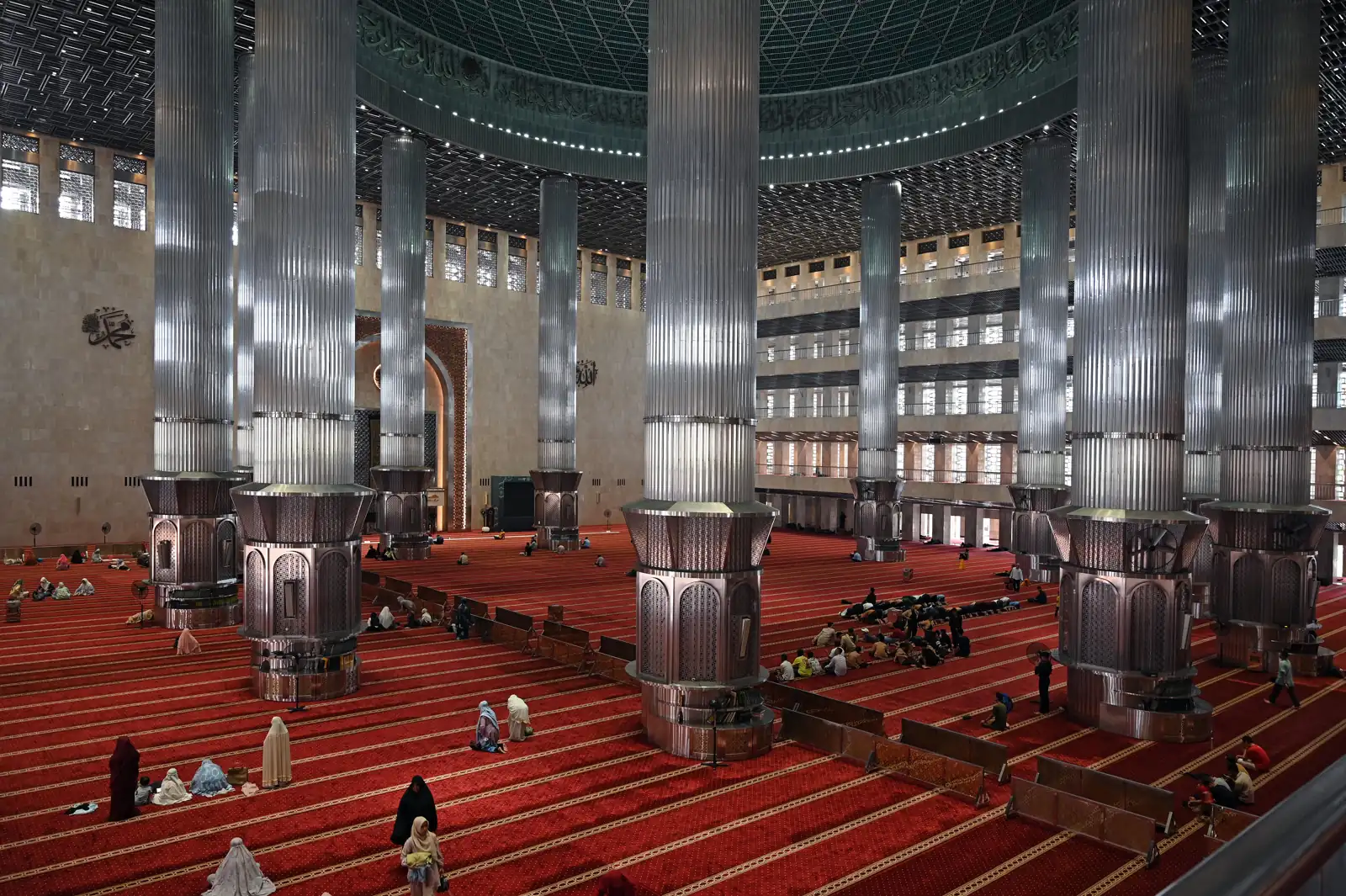 ruang salat utama Masjid Istiqlal dengan tiang-tiang besar berlapis logam dan karpet merah