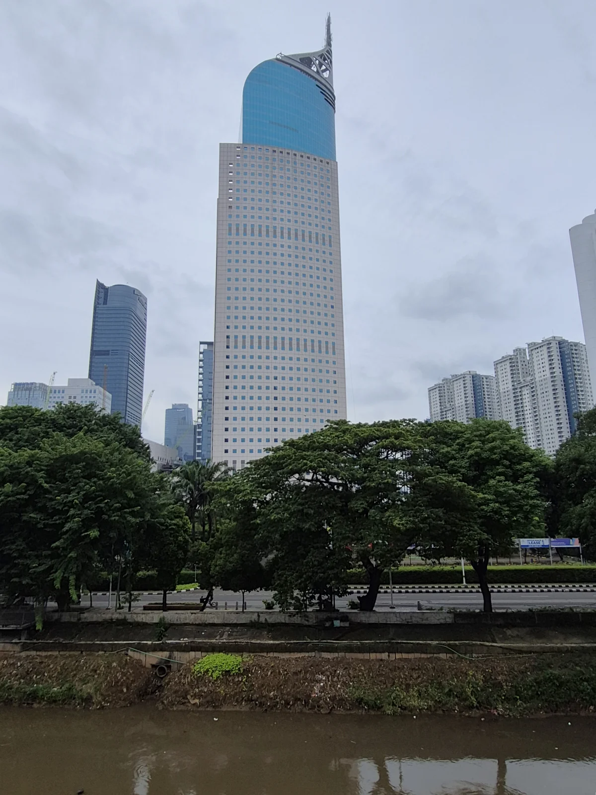 menara Wisma 46 berpuncak runcing biru di tepi kali Sudirman
