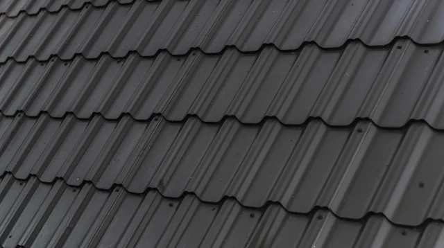 Atap rumah berlapis genteng metal hitam bermotif gelombang yang tersusun rapi