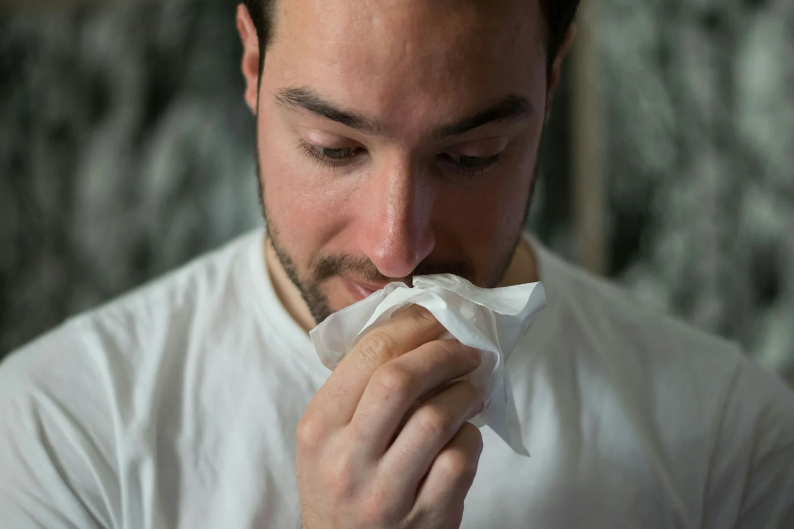 pria pilek menutup hidung dengan tisu