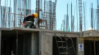 pekerja di atas balok beton lantai yang sudah dicor dengan rangkaian besi tulangan dan sengkang kolom menjulang di atasnya