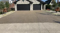 Carport dan jalan masuk rumah berlantai batu sikat exposed aggregate dengan koral kecil, separuh bagian depan belum dilapisi coating