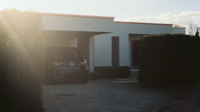 Carport minimalis beratap datar menyatu dengan rumah modern putih, mobil terparkir di bawahnya