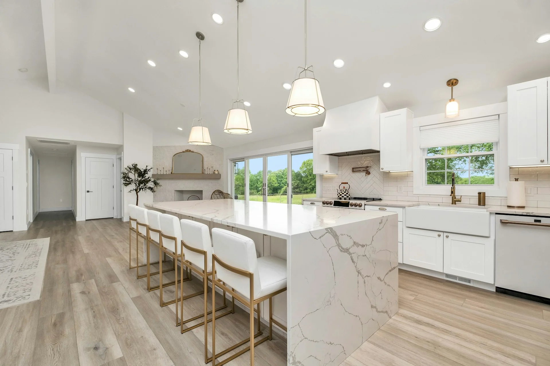 Dapur bersih modern dengan kitchen island marmer putih, kursi bar, dan kabinet putih