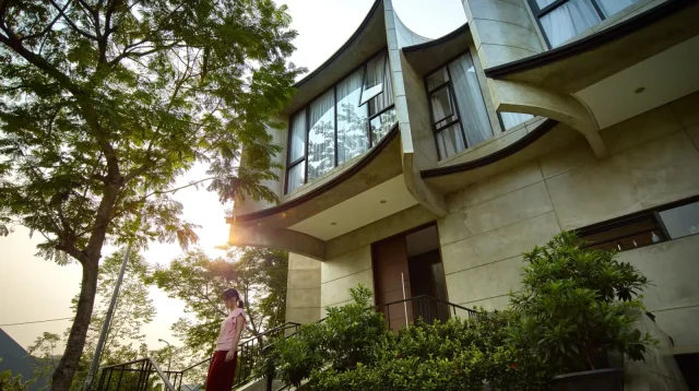desain rumah tropis Kampono House dengan sirip beton melengkung di antara pepohonan