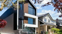 Fasad rumah dua lantai sempit bergaya modern dengan panel kayu, jendela kaca lebar, dan tangga depan