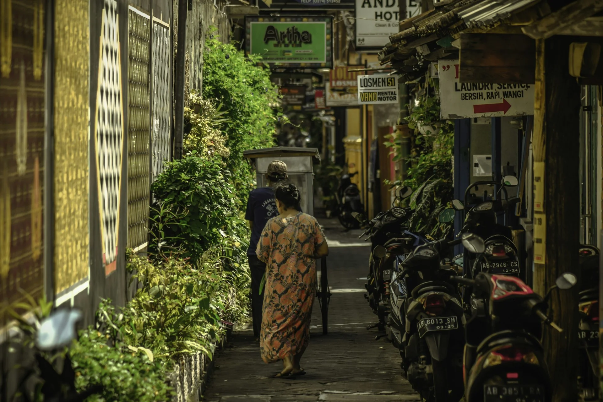 gang sempit lokasi rumah 2 lantai sederhana di kampung, dengan sepeda motor terparkir di satu sisi