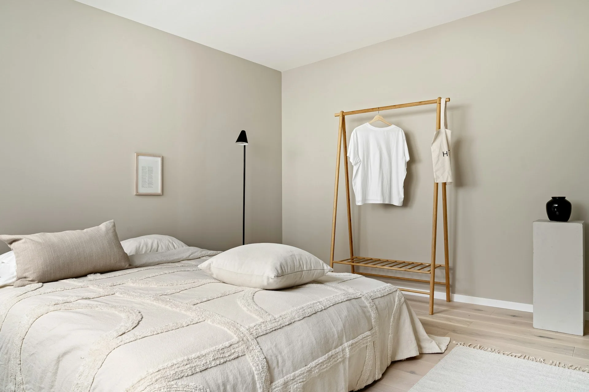 kamar-tidur-aesthetic-warm-minimalism-beige Kamar tidur aesthetic bernuansa krem dengan seprai linen beige, lantai kayu muda, dan rak gantung baju dari kayu