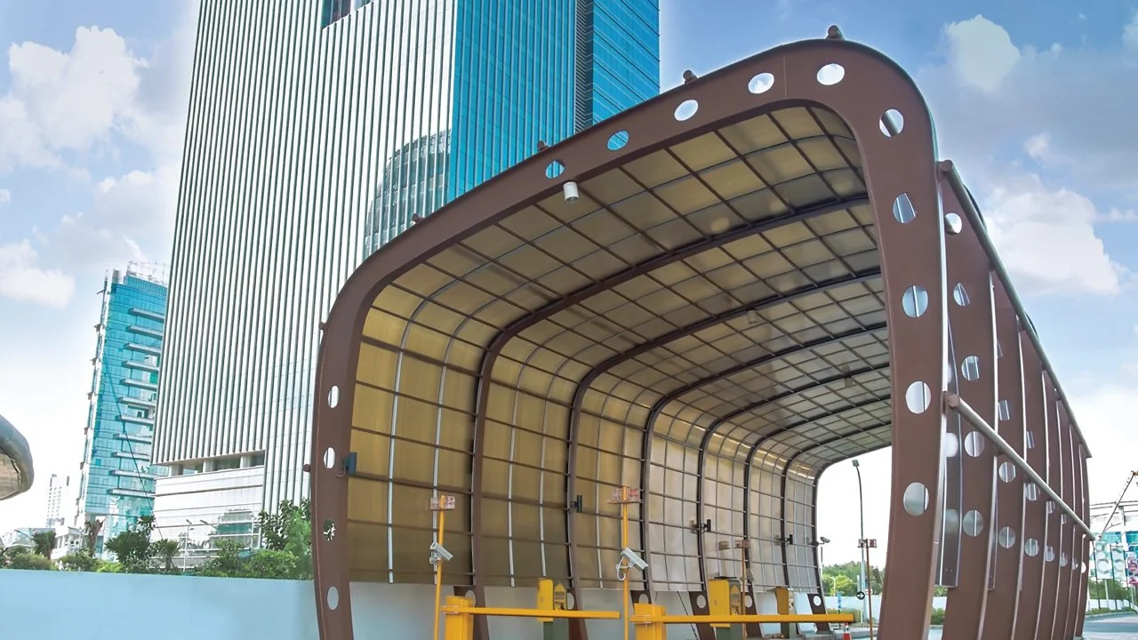 Kanopi lorong melengkung beratap polycarbonate Twinlite warna bronze di depan gedung perkantoran