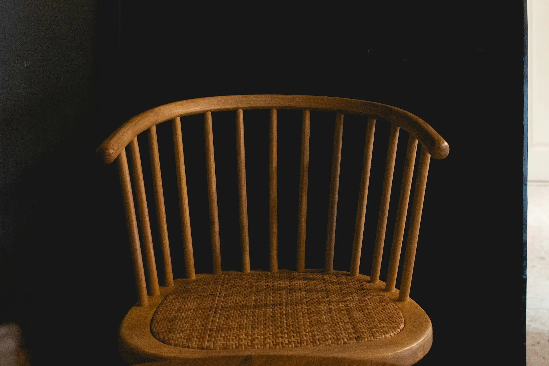 Kursi kayu bersandaran jeruji dengan dudukan anyaman rotan, contoh furnitur rumah japandi