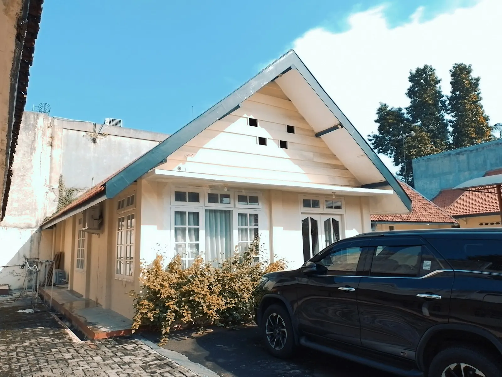 mobil parkir di halaman rumah tanpa kanopi