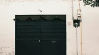 Contoh model pagar besi minimalis mewah: pintu pagar plat besi hitam polos dua daun pada dinding plester putih