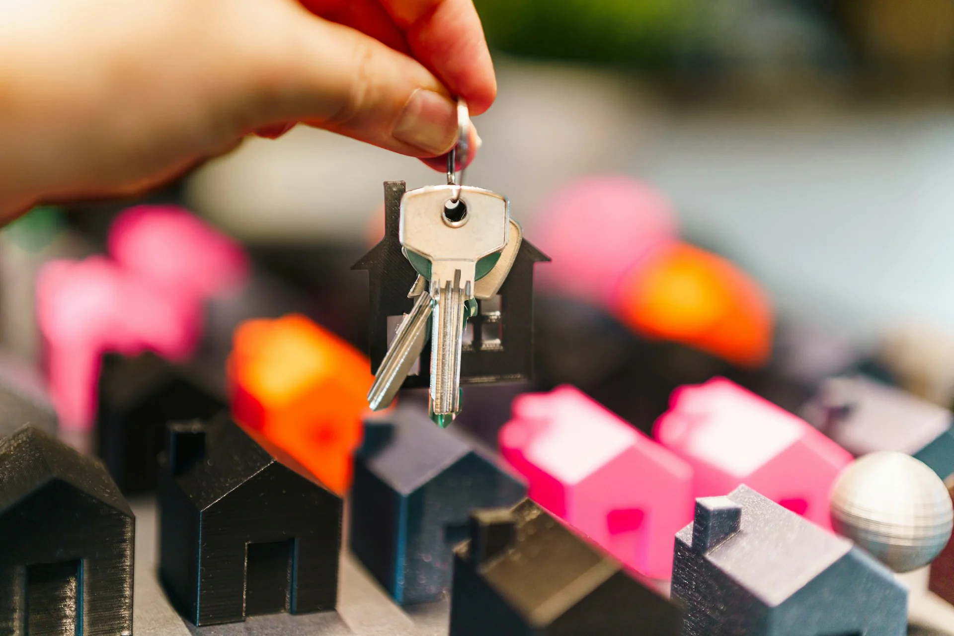 Tangan memegang kunci rumah di atas miniatur rumah