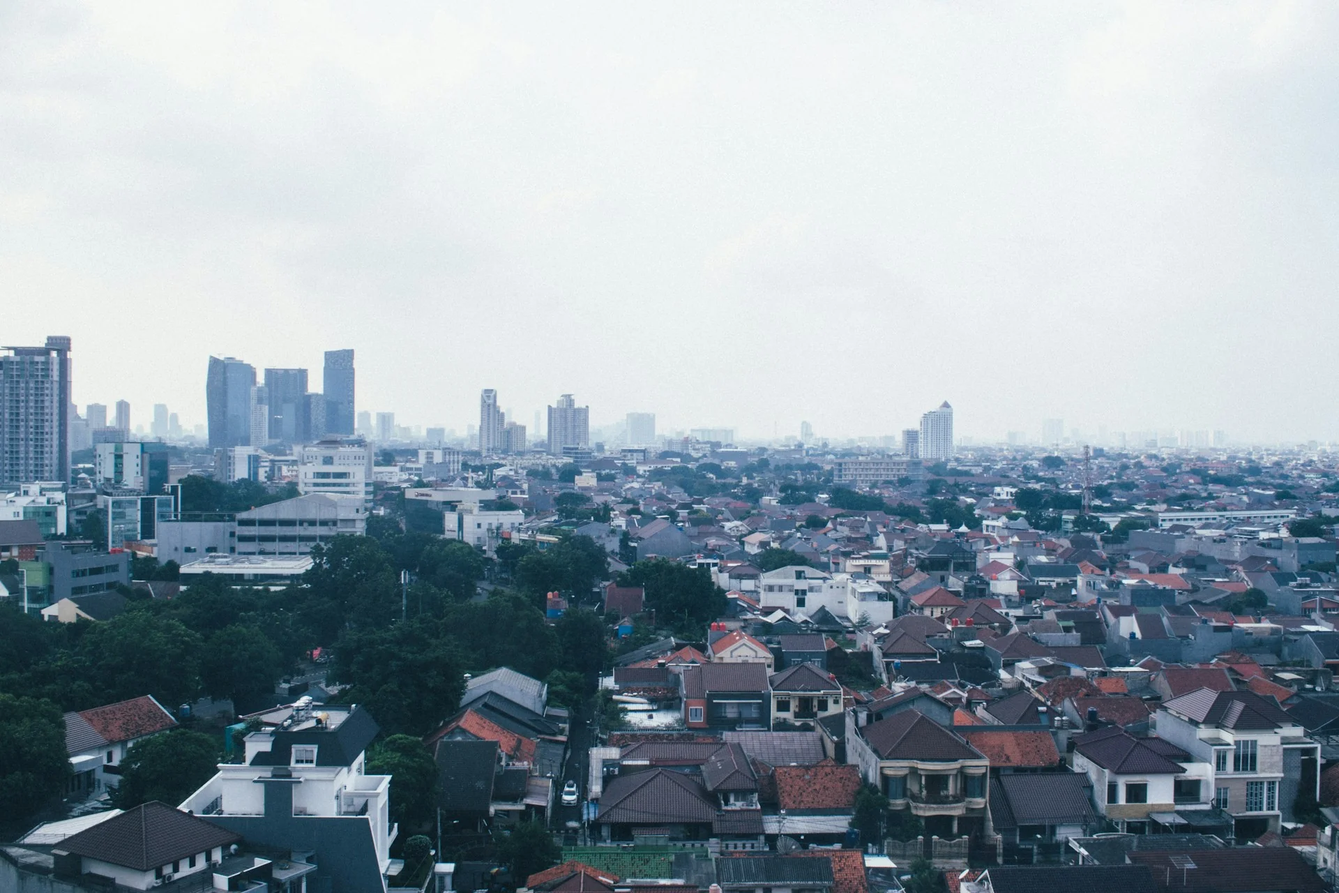 Hamparan rumah tapak beratap genteng di Jakarta dengan gedung tinggi di kejauhan