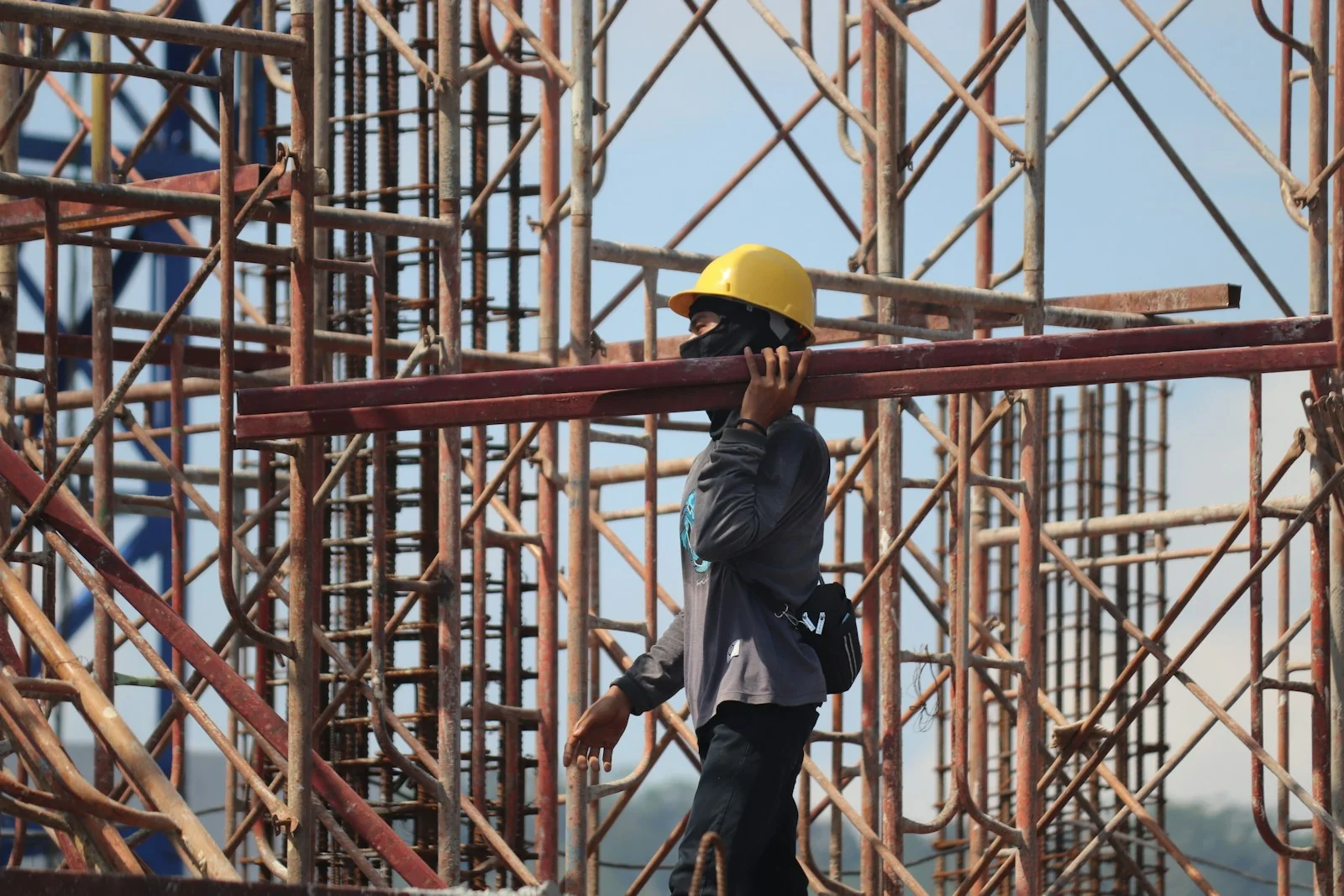 pekerja memikul besi di proyek bangunan