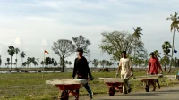 Tiga pekerja bangunan mendorong gerobak berisi panel beton untuk proyek rumah di Aceh