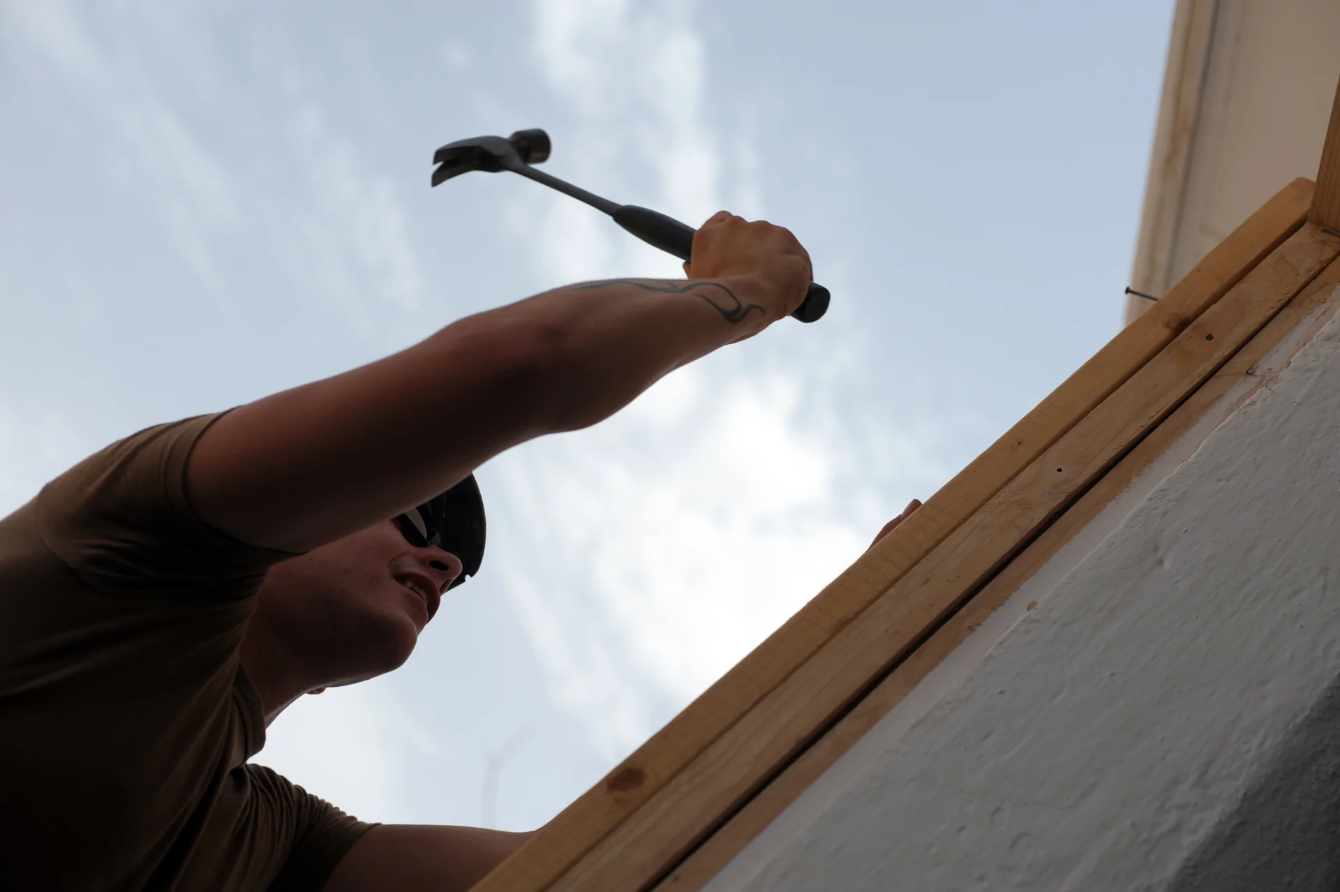 pemasangan-kusen-pintu-kayu tukang memaku ambang atas kusen pintu kayu pada dinding