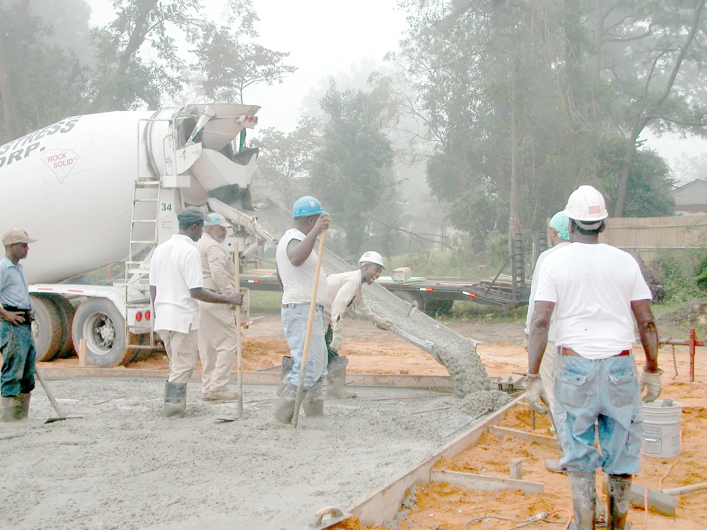 pekerja meratakan beton segar dari truk molen