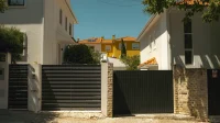 Dua pintu pagar sliding besi bilah horizontal di depan rumah putih