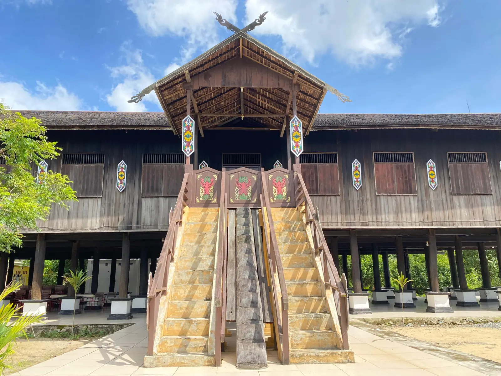 Rumah Betang panggung panjang dari kayu dengan tangga kayu di depan
