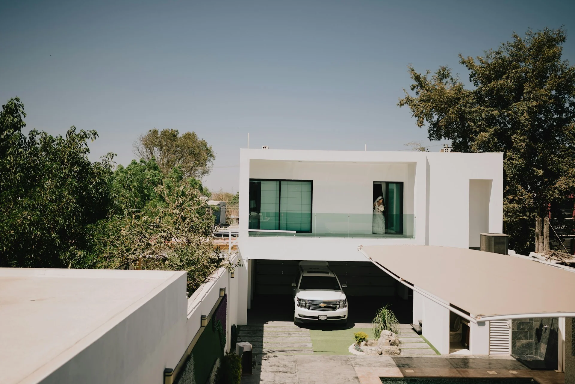 Rumah 2 lantai minimalis modern bercat putih beratap dak datar dengan carport di lantai bawah