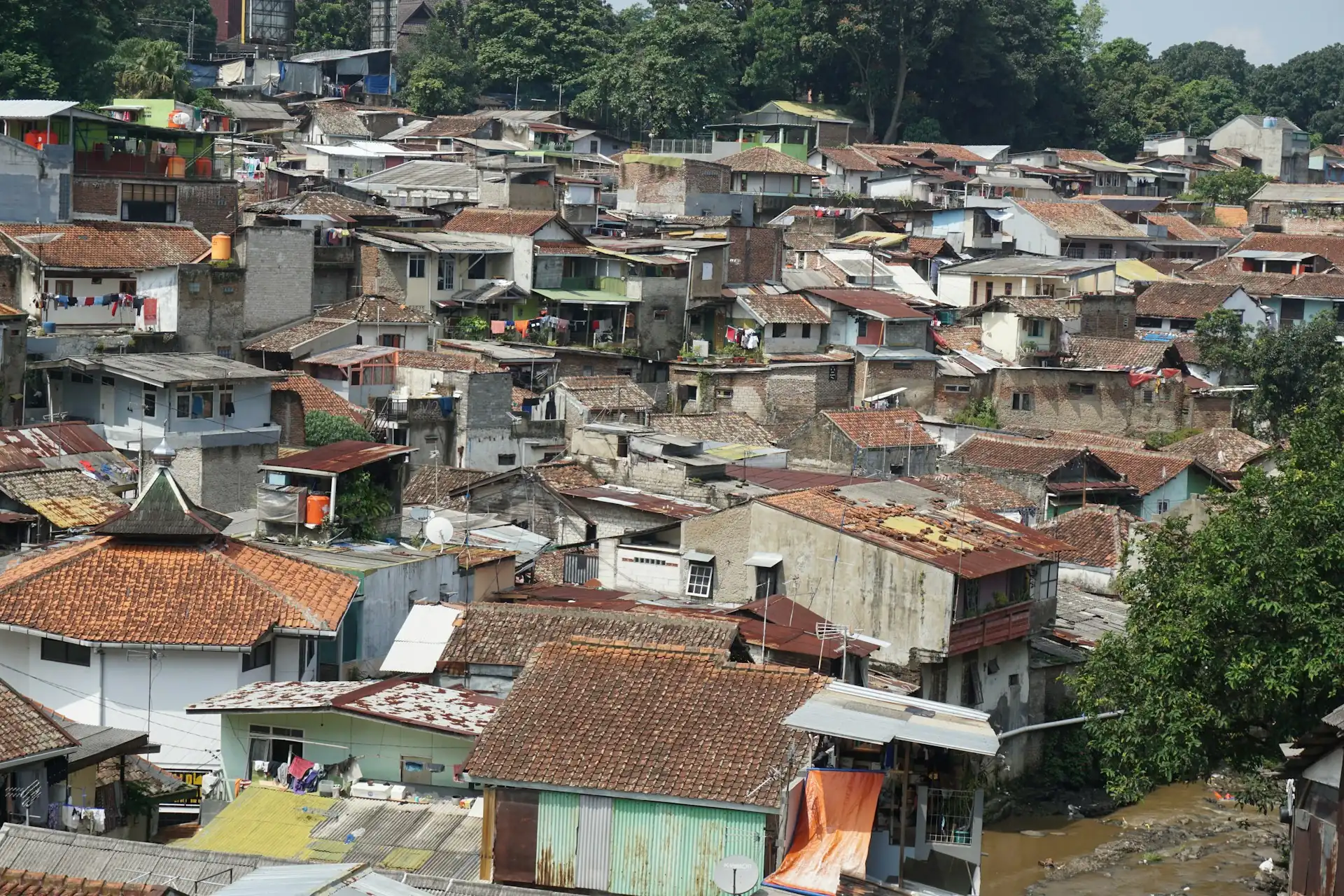deretan rumah dua lantai berdinding bata dan beratap genteng berimpitan di permukiman padat tepi sungai