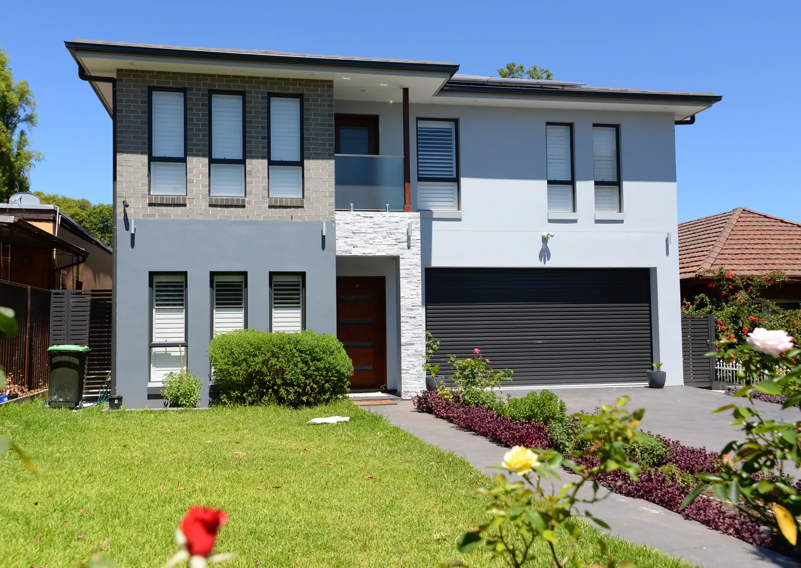 rumah modern dua lantai dengan fasad abu-abu dan carport