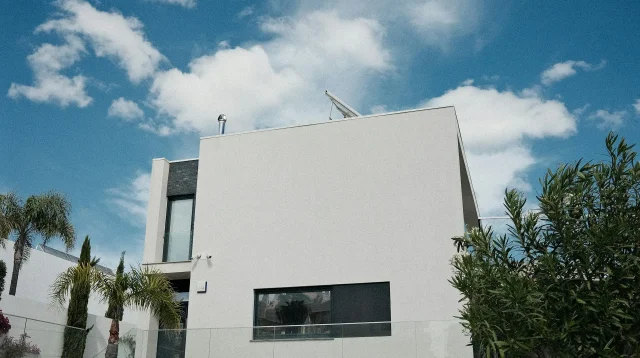 rumah modern putih dengan jendela besar dan pohon palem