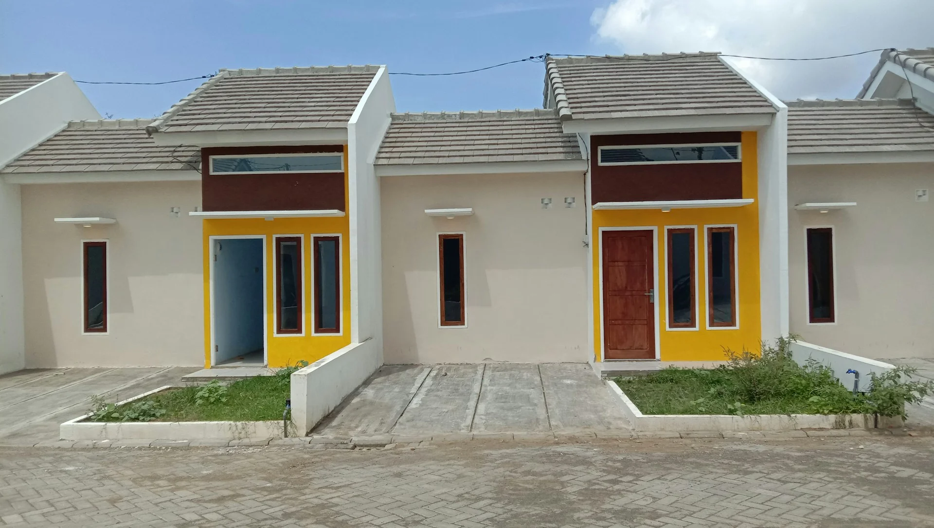 deretan rumah tipe kecil di perumahan dengan halaman depan terbuka, belum berpagar dan belum berkanopi