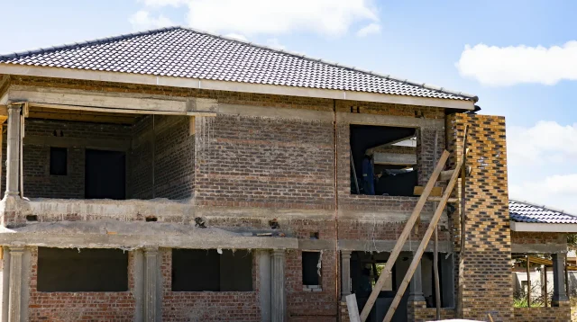 rumah sedang dibangun dengan dinding bata merah, kolom beton, dan perancah kayu