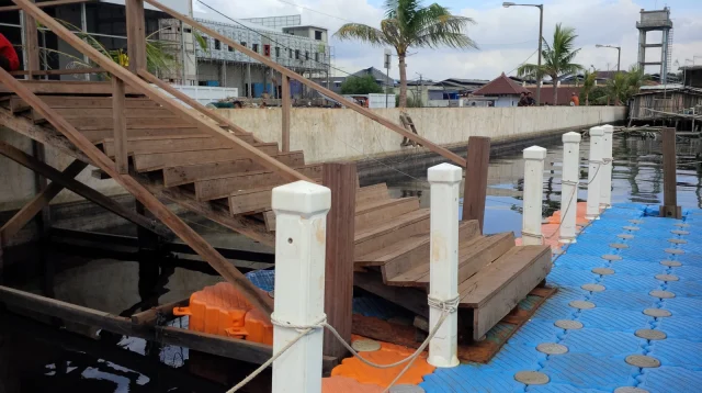 saluran air di Muara Baru dengan tembok tanggul tinggi di belakangnya