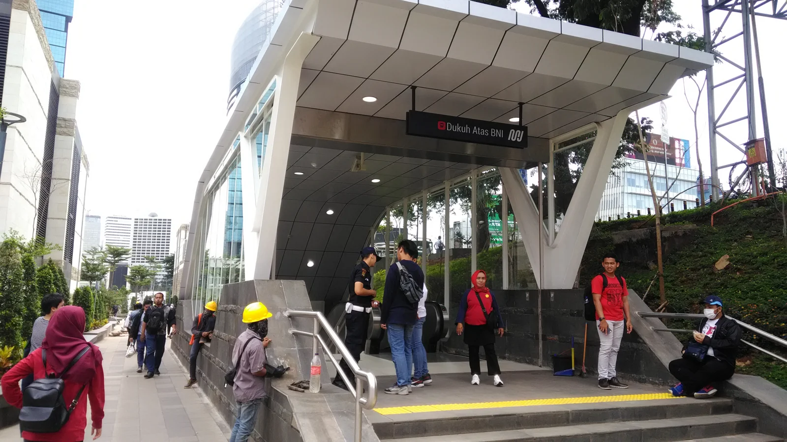 pintu masuk Stasiun MRT Dukuh Atas dengan kanopi putih dan penumpang