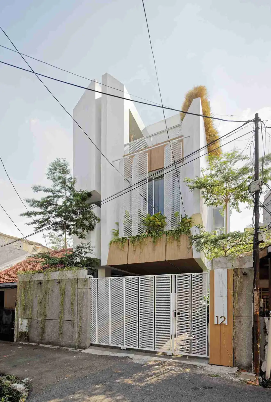 rumah tiga lantai putih dengan taman di lantai atas dan pagar putih