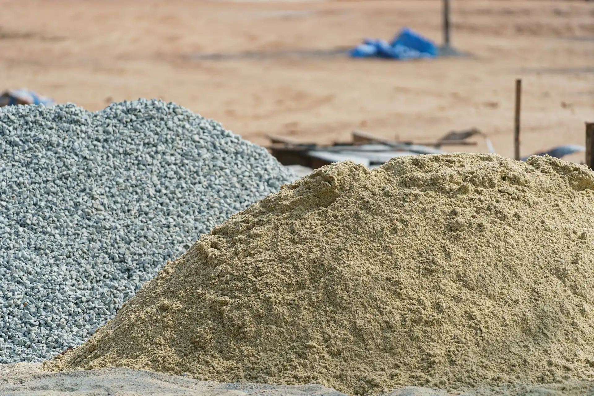 Tumpukan pasir kasar di samping batu split di proyek; harga pasir per kubik dan harga split dihitung terpisah